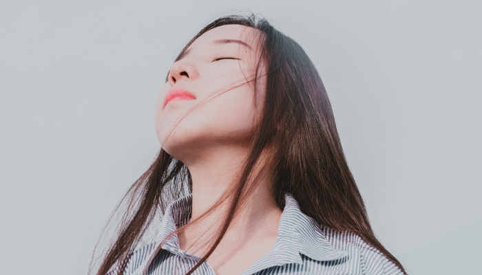 Brunette woman breathes in deeply with closed eyes as she tries to overcome her dental anxiety