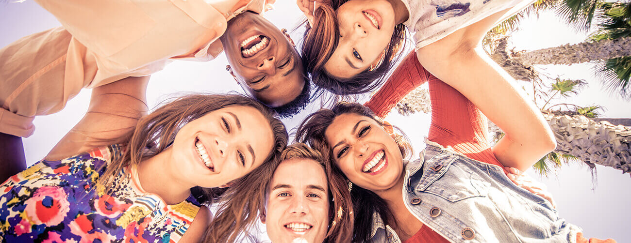a group of friends in a circle looking down and smiling