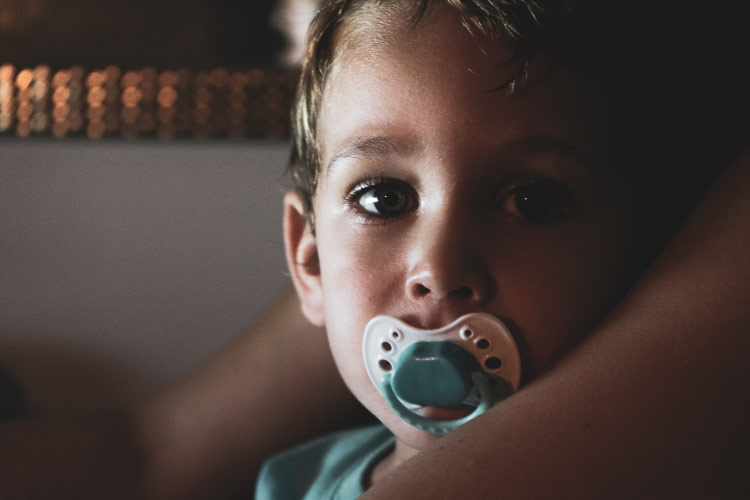 young boy sucking on a pacifier