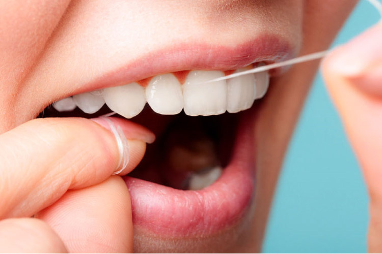 closeup of a woman flossing her teeth