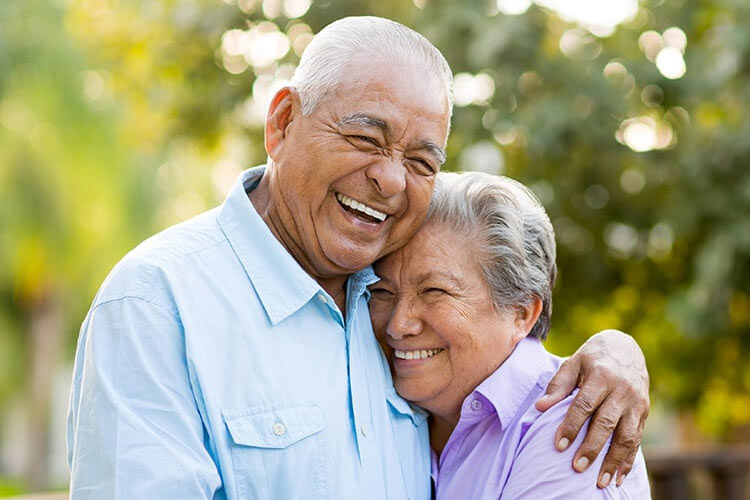 senior couple hugging and smiling after learning about dentures