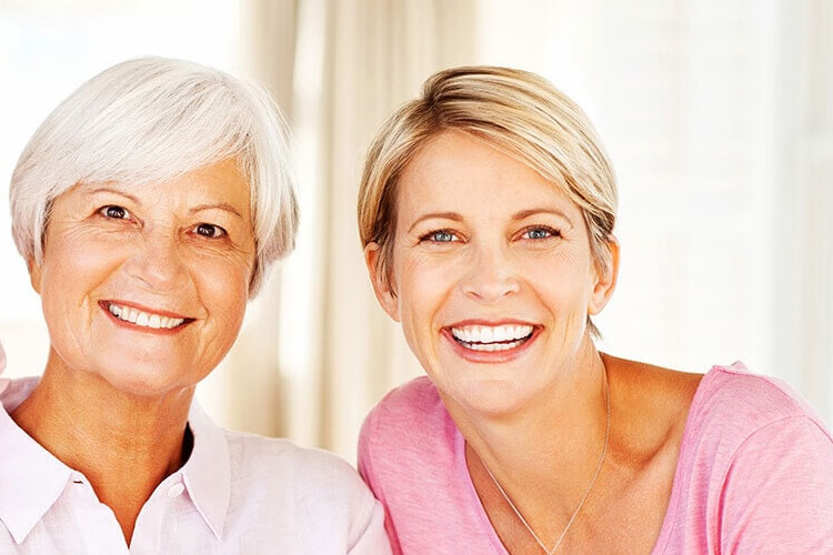 two women smile to show off their veneers and lumineers