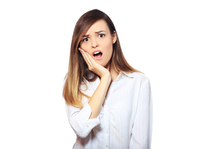 young woman holding her jaw in pain with a dental emergency